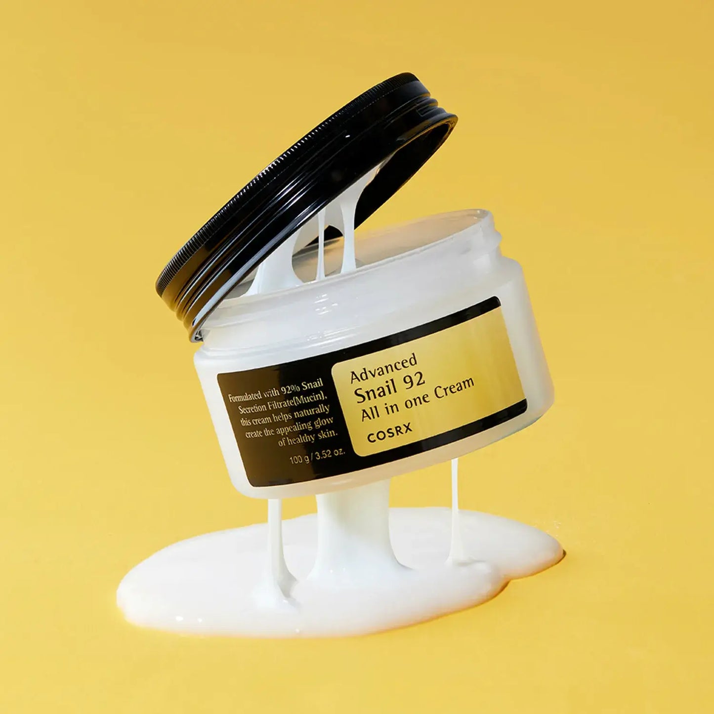 COSRX Advanced Snail 92 All-in-One Cream jar with cream oozing out against a yellow background, ideal for glowy skin.