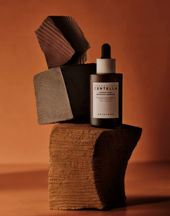 Skin1004 Madagascar Centella Probio-Cica Intensive Ampoule on a textured display for skincare promotion.