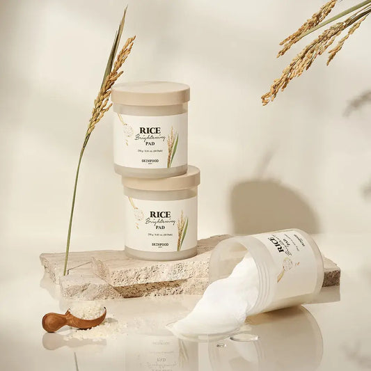 Two jars of SKINFOOD Rice Brightening Pads on a stone surface, showcasing their natural ingredients for radiant skin.