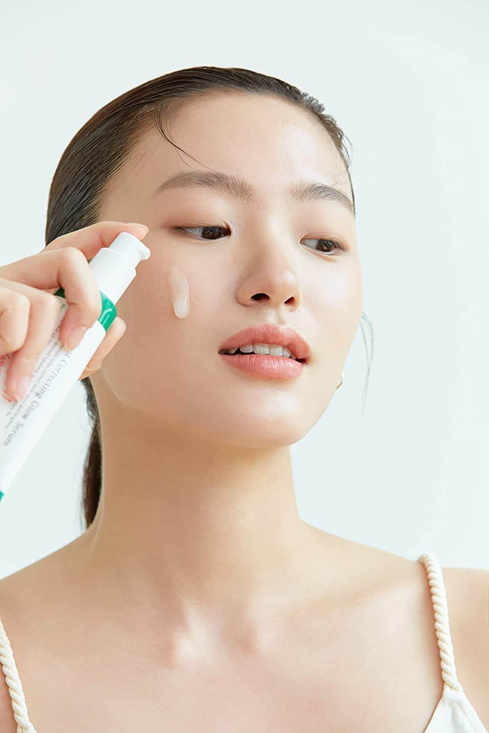 Woman applying AXIS-Y Dark Spot Correcting Glow Serum to her face for a glowy, healthy skin look.